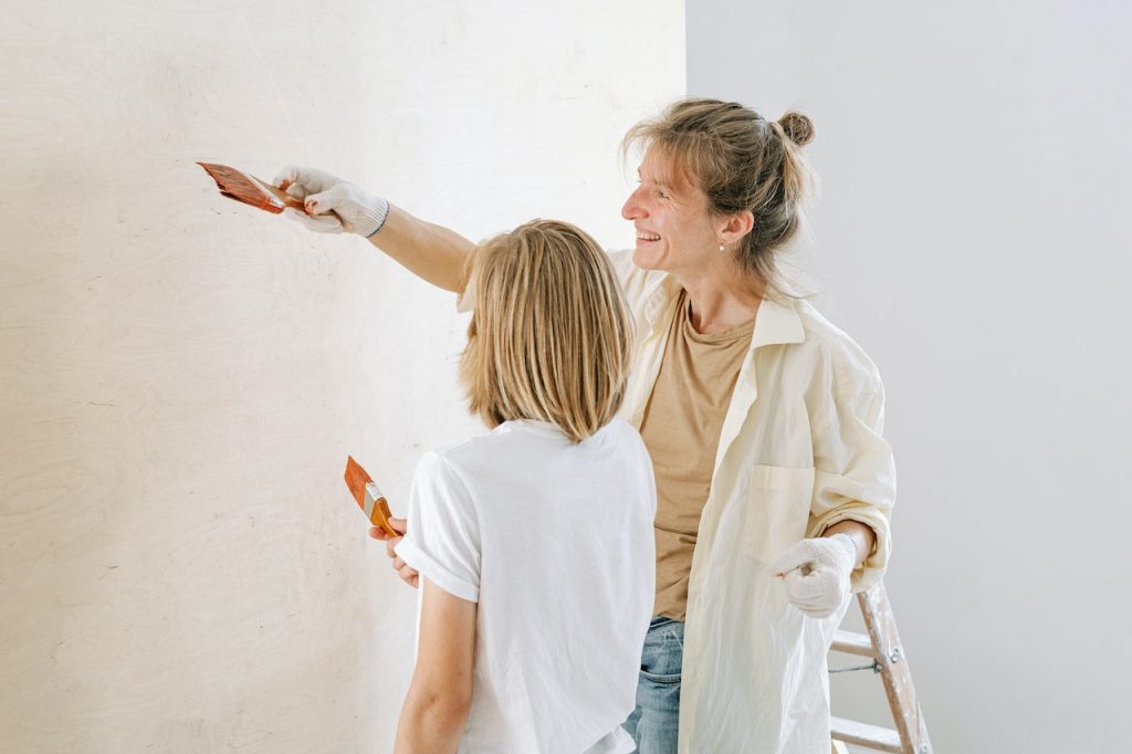 Mother and son working together on repainting a wall in their living room